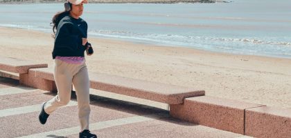 A woman jogs along the beachfront pathway in Montevideo, Uruguay, enjoying a sunny day.