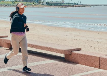 A woman jogs along the beachfront pathway in Montevideo, Uruguay, enjoying a sunny day.
