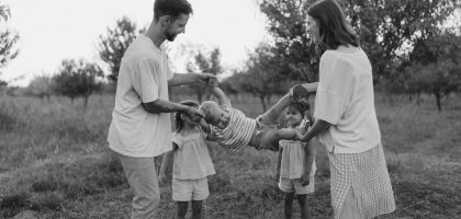 Family playing with child in grassy field