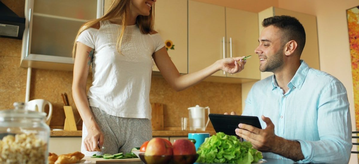 🎬 FULL 4K VIDEO for this still is in my bio link! ⬇️ Attractive couple chatting in the kitchen early morning. Beautiful woman feed her husband while cooking breakfast at home