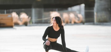 woman in black tank top and black leggings holding black and white nike shoes