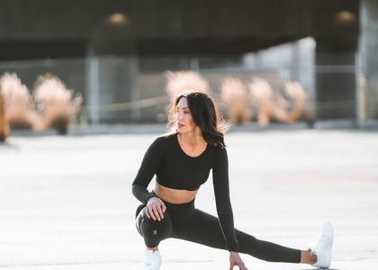 woman in black tank top and black leggings holding black and white nike shoes